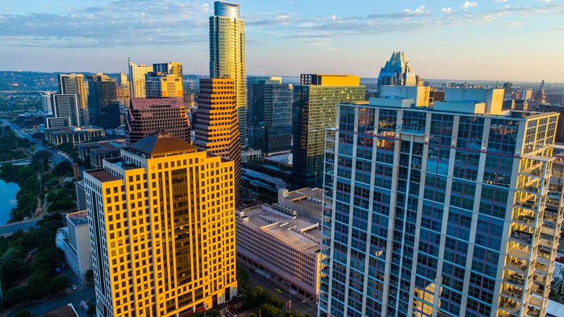 Austin city in Texas at sunrise with golden rays bathing an apartment townhouse and other buildings.